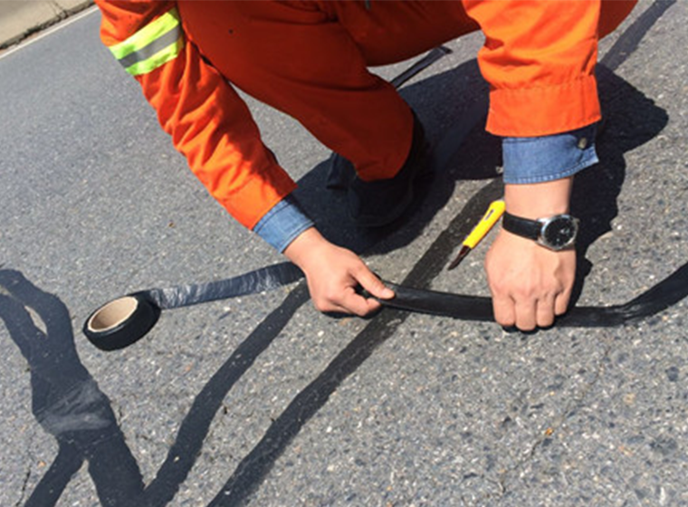Self-adhesive tape for quick and flexible asphalt crack sealing.